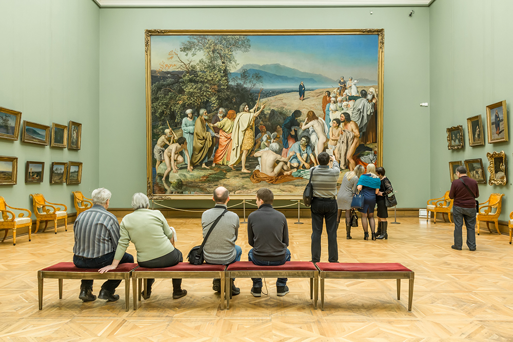 People sitting in front of a painting a museum