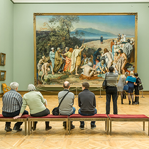 People sitting in front of a painting in a museum