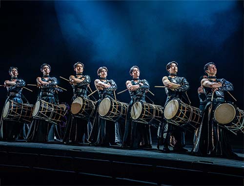 Image of asian drummers performing energetically on stage, showcasing traditional rhythms and vibrant costumes