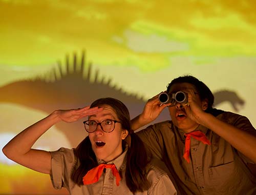 Two people in colorful costumes looking through binoculars, enjoying a fun outdoor activity together.