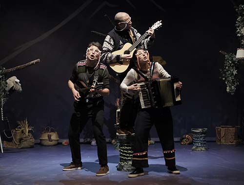 Three musicians are on stage, playing instruments and entertaining the crowd with their performance.