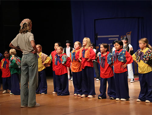 Image of kids practicing their lines with play's director