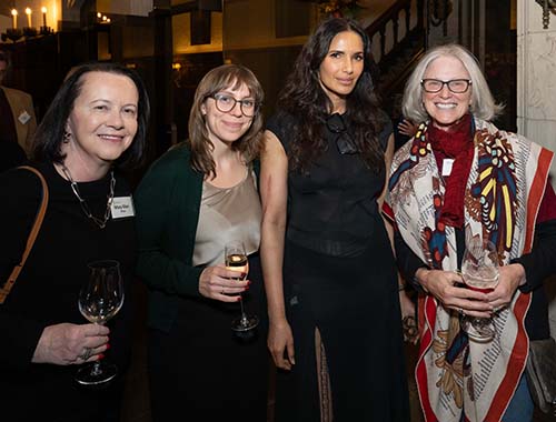 A group of four women happily posing for a picture at an event.