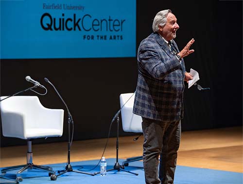 Image of a man speaking on stage at a Quick Center event, engaging the audience with his presentation.